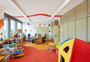 Foto eines Eltern-Kind-Zimmers beim BKA: ein Büro mit Schreibtisch und Spielecke.